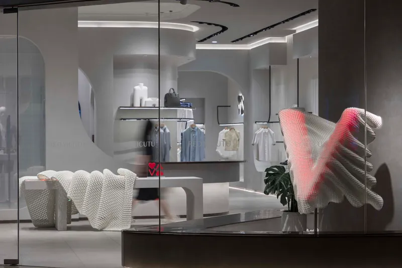 View through glass storefront showing textured seating and undulating ceiling cove with integrated lighting
