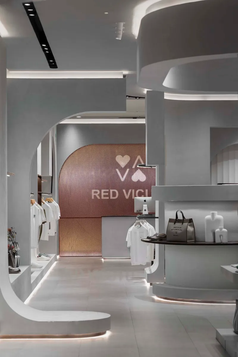 Arched portal with copper mesh screen backdrop connecting retail zones with curved white millwork
