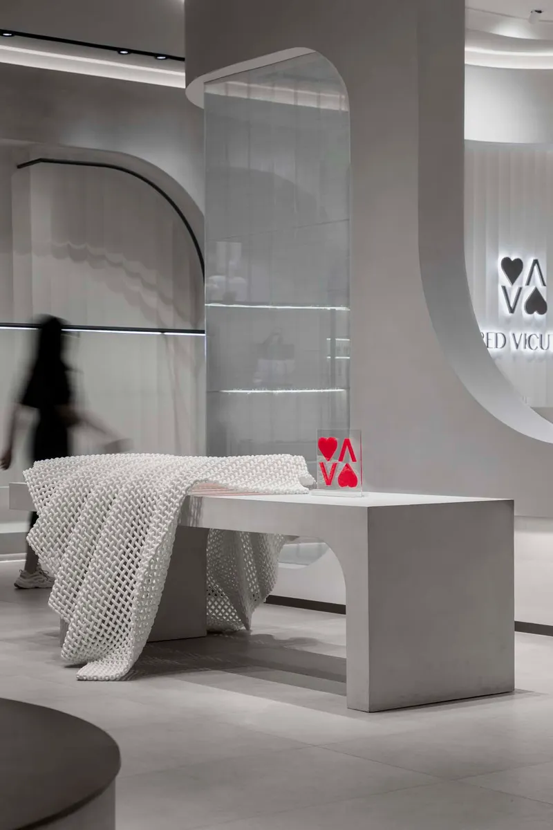 White bench draped with textured throw beside curved wall and person in motion