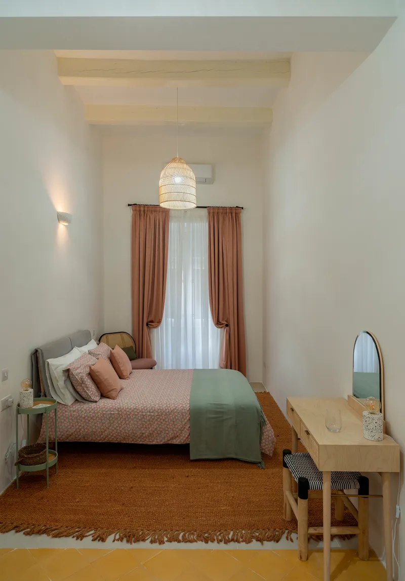 Bedroom with exposed timber ceiling beams and a woven pendant light above the bed