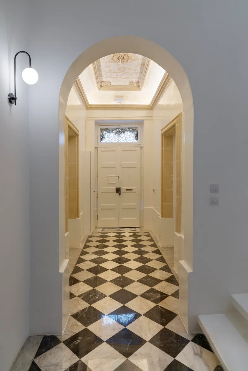 Entry hall viewed through an arch with checkerboard marble flooring and a skylight above