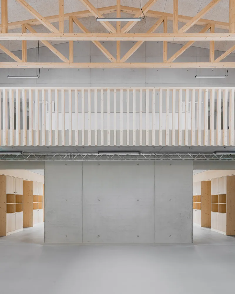 Vertical batten balustrade overlooking concrete wall with plywood shelving units below timber truss ceiling