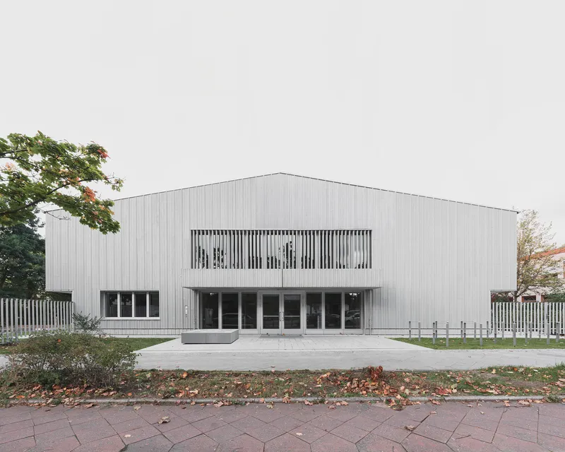 Front elevation with vertical screen strip windows on corrugated metal facade in autumn leaves