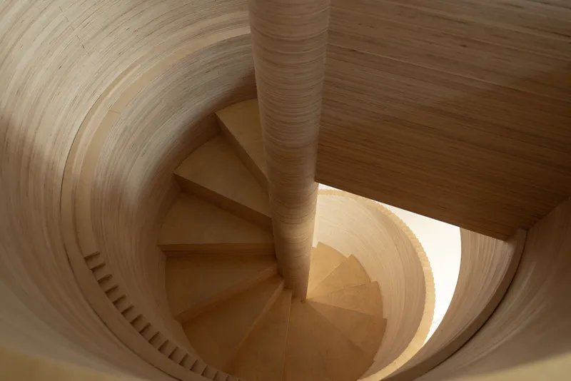 View looking down the curved timber spiral staircase showing continuous grain and central newel