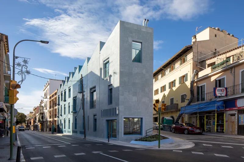 Corner facade clad in white tile facing a street intersection in afternoon light