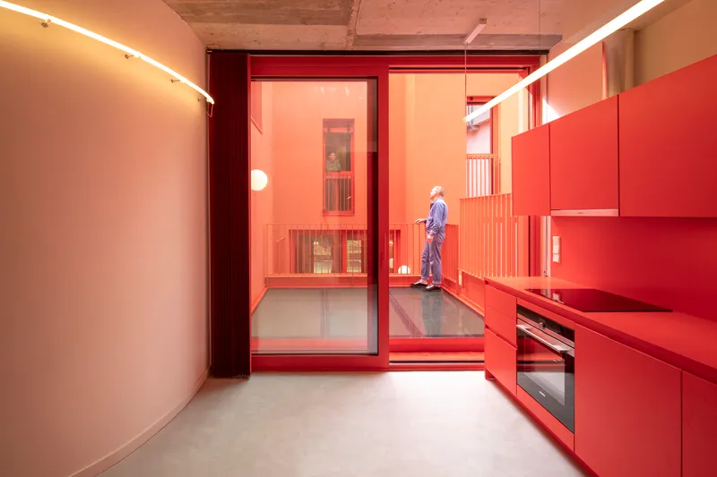 Kitchen with red cabinetry and sliding glass door opening to a terrace with timber ceiling