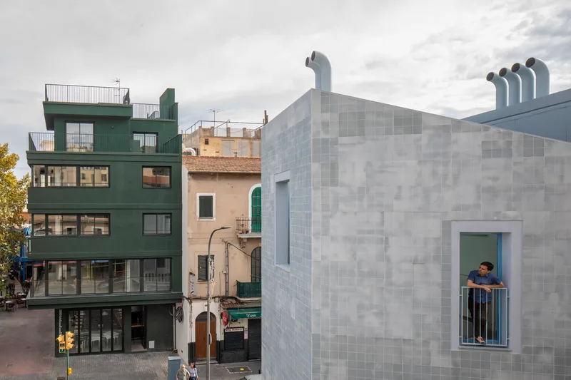Tiled facade with recessed balcony window occupied by a person under cloudy skies