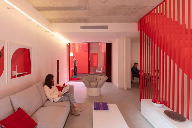 Interior with red slatted staircase screen and view through glazed courtyard where two people stand