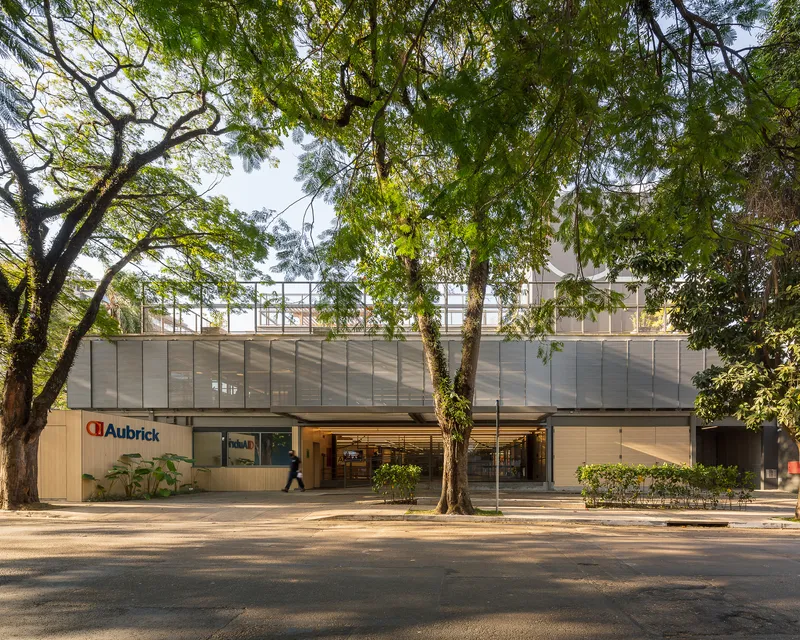 Street view of the two-story facade with translucent upper panels and glass entrance framed by mature trees