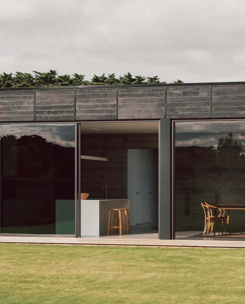 Garden elevation showing full-height glazing below horizontal timber cladding with trees in the background