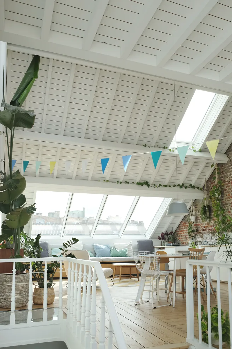 Attic space with painted timber ceiling, angled skylights and colorful fabric bunting strung overhead