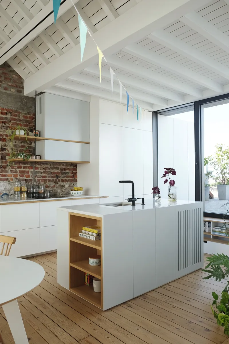 Kitchen island with integrated shelving and fluted panel detail beneath a white painted beam ceiling
