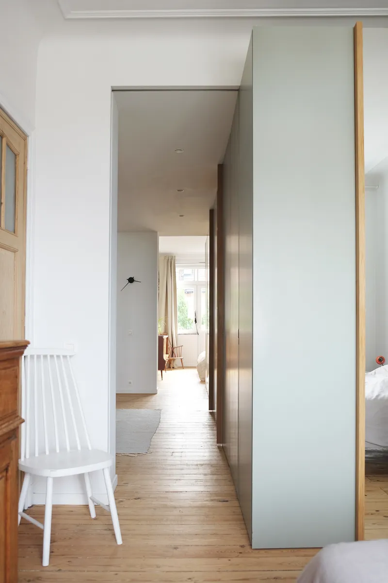 Interior hallway framed by grey panels with timber edging and light-filled passage leading to distant rooms