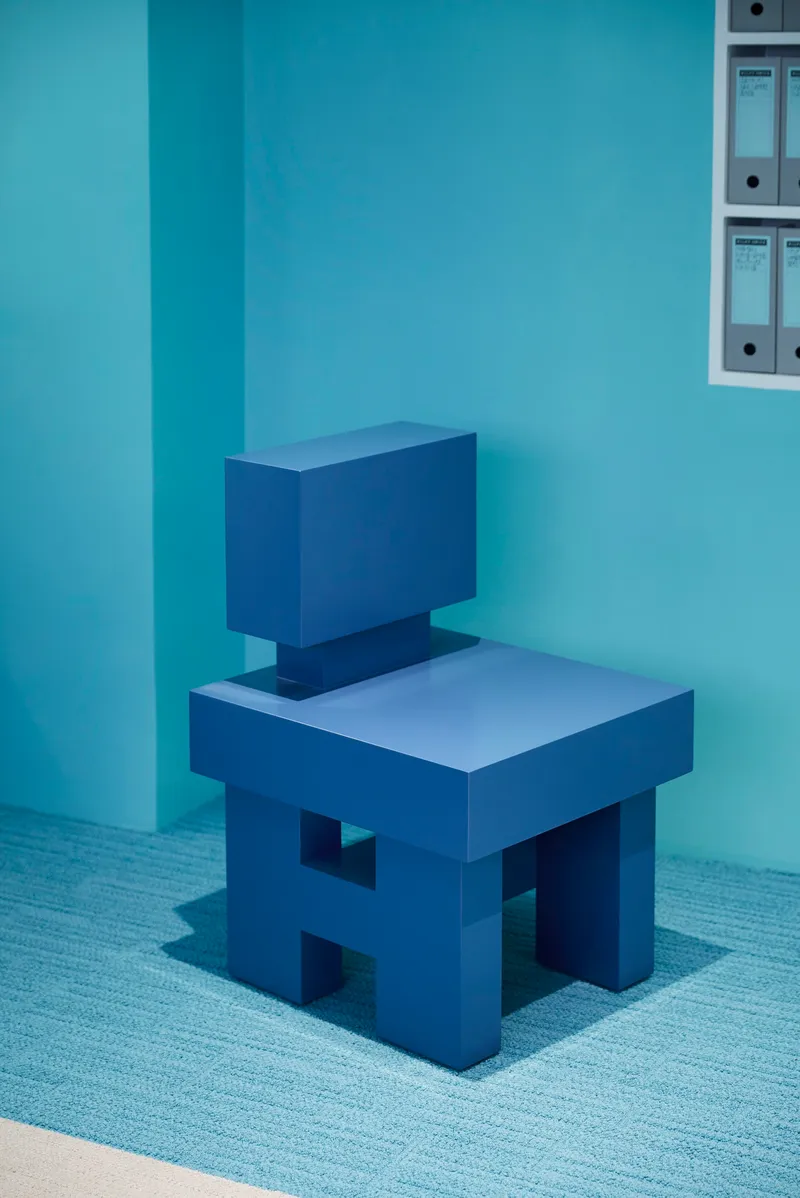 Geometric chair form with rectangular seat and back in solid blue against a corner