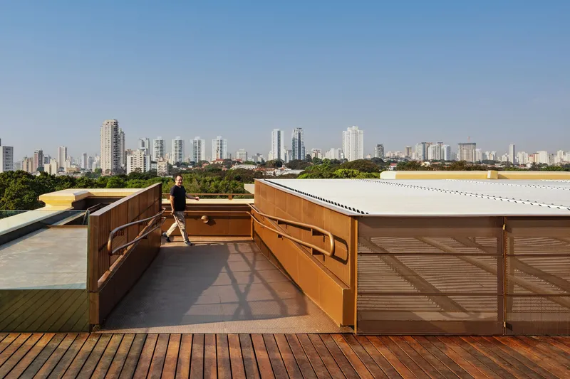 Rooftop terrace with timber louvers, decking, and a person walking with city skyline beyond
