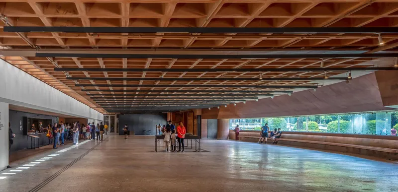 Gallery space with timber coffered ceiling and long windows framing garden views and visitors
