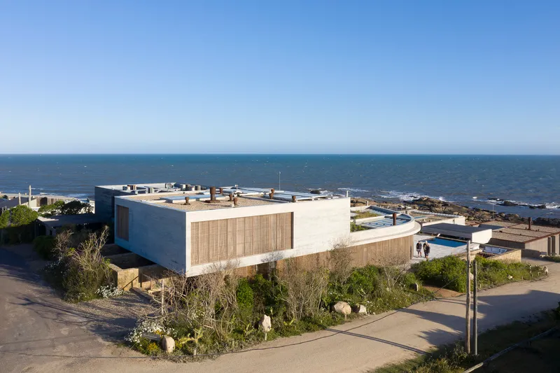 Elevated view of the concrete and timber-screened volume set among planted beds overlooking the ocean