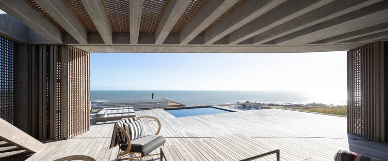 View through the pavilion opening toward the infinity pool deck and ocean horizon in bright daylight