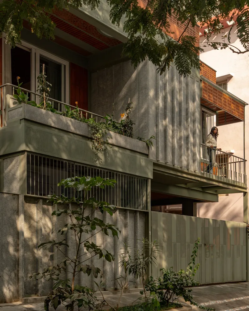Planted balconies and vertical concrete cladding with dappled tree shadows at dusk