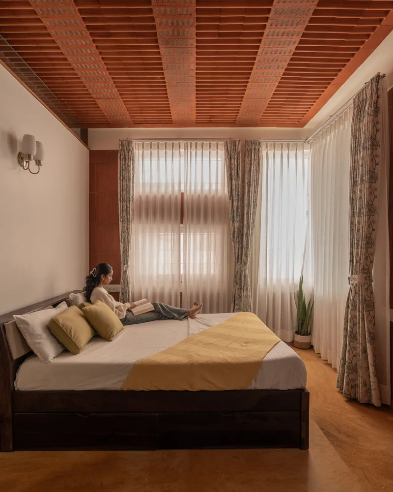 Bedroom with timber-slatted ceiling and sheer curtains diffusing soft morning light