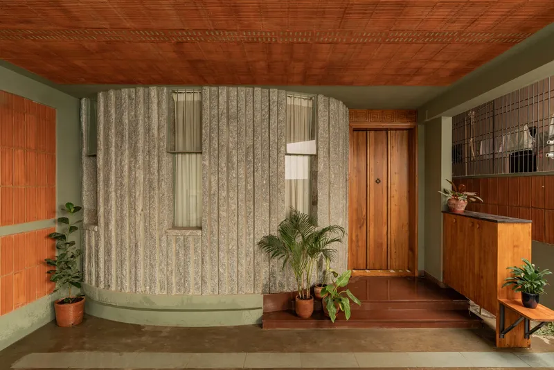Entry foyer with curved concrete wall, patterned wallpaper, and perforated brick ceiling