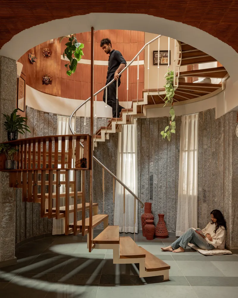 Spiral staircase with timber treads and steel railing framed by an arched opening with occupants