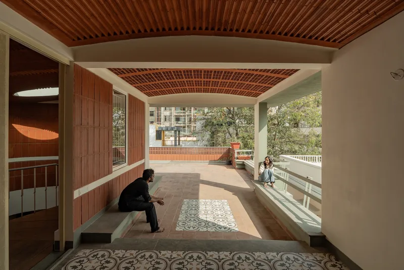 Covered terrace with perforated brick ceiling, patterned floor tiles, and built-in benches