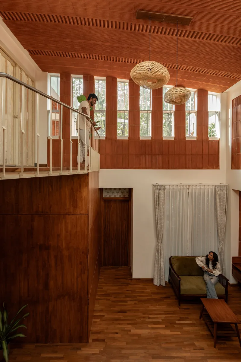 Double-height living space with slatted wood ceiling and clerestory windows above a mezzanine bridge