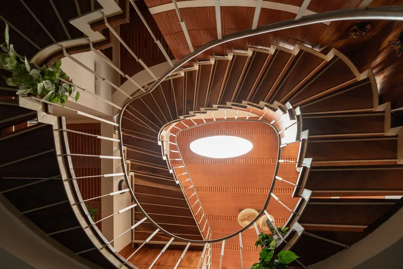 Top-down view into the spiral stairwell showing timber treads radiating around the central void