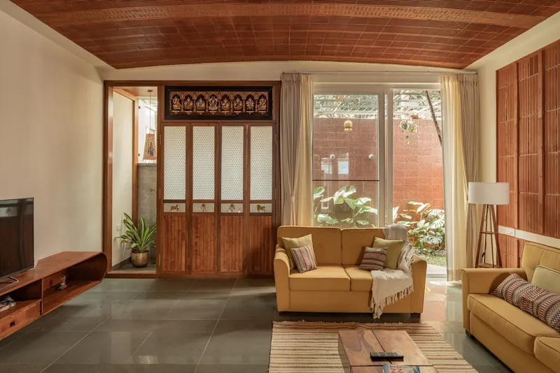 Living room with timber screen doors, slatted wood ceiling and courtyard view through glazed doors