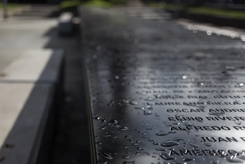 Close-up of engraved names on wet black granite surface with water droplets