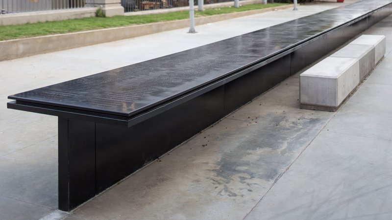Extended view of the black granite memorial bench alongside white concrete block seating
