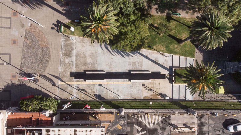 Aerial view of a concrete plaza bordered by palm trees and a planted median strip