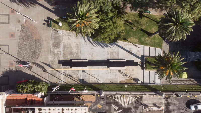 Aerial view of a concrete plaza bordered by palm trees and a planted median strip