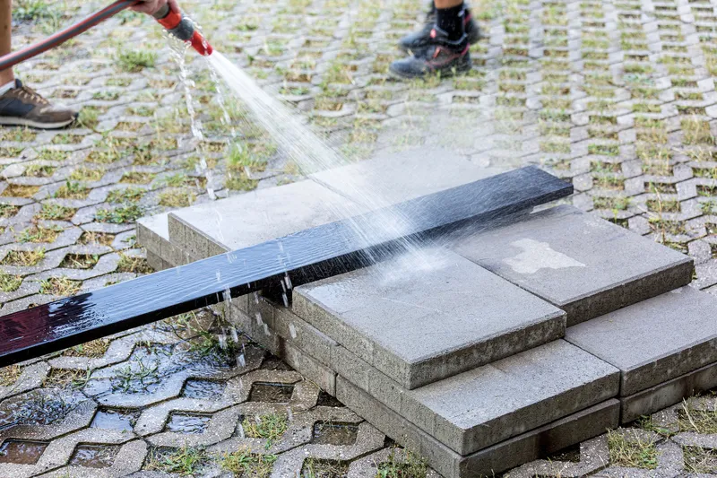 Water being sprayed from a hose onto the charred timber bench during installation or cleaning