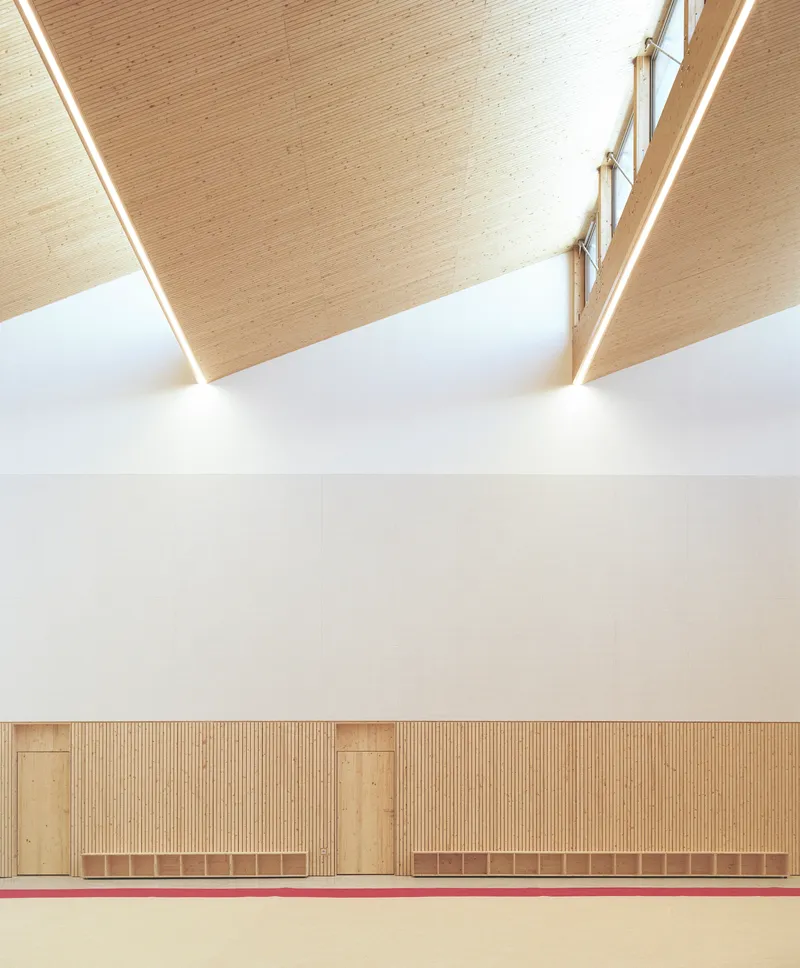 Sawtooth ceiling detail with timber planks, clerestory windows and timber-paneled wainscoting below white wall