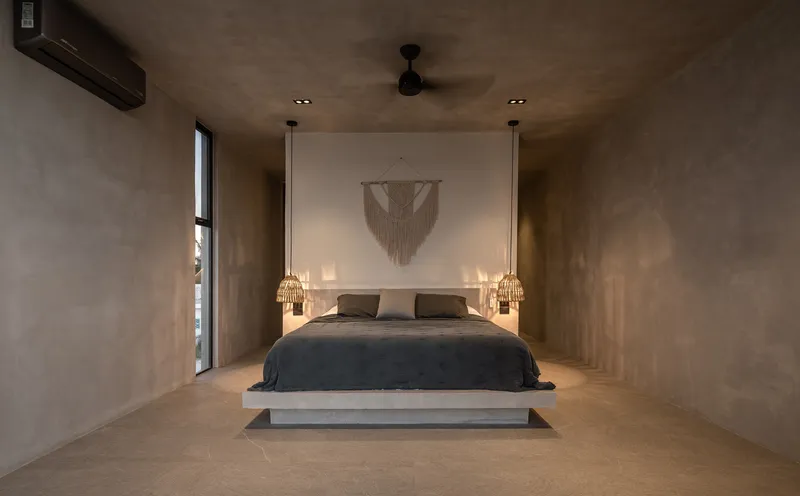 Bedroom with polished concrete platform bed and recessed illuminated alcove behind the headboard