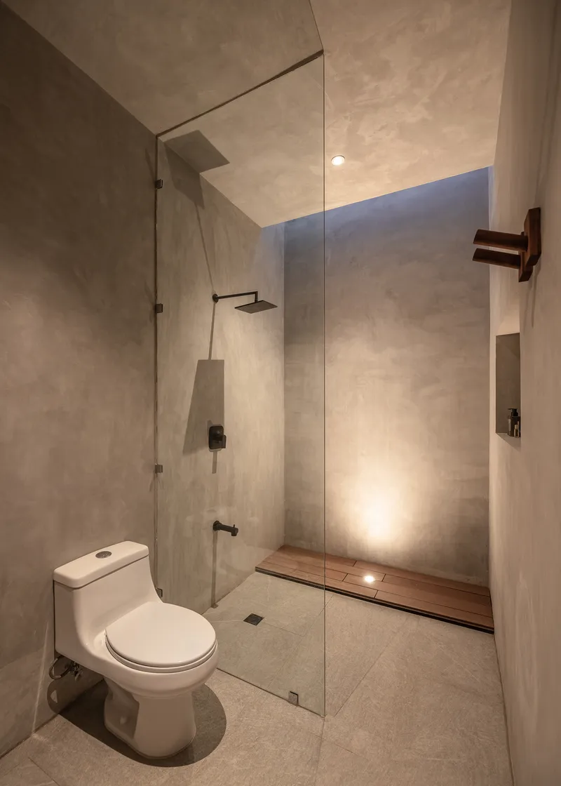 Bathroom with glass-enclosed shower area, wall-mounted toilet and skylight slot above