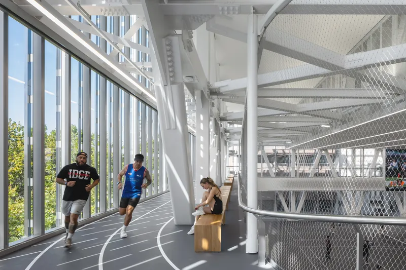 Interior running track with vertical white fins and white structural columns in bright daylight