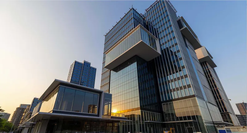 Cantilevered volumes with vertical metal fins and glass curtain wall at twilight