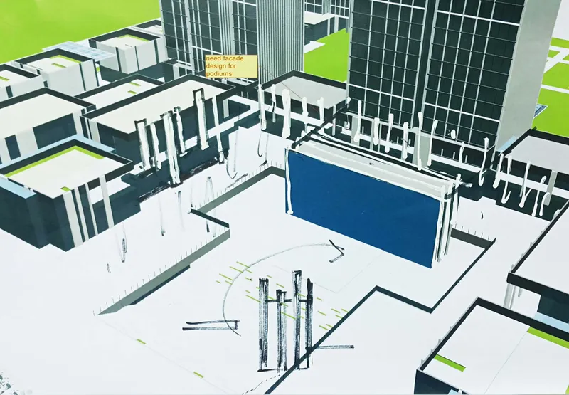 Aerial view of a plaza with vertical sculptural elements and a blue wall beside tower bases