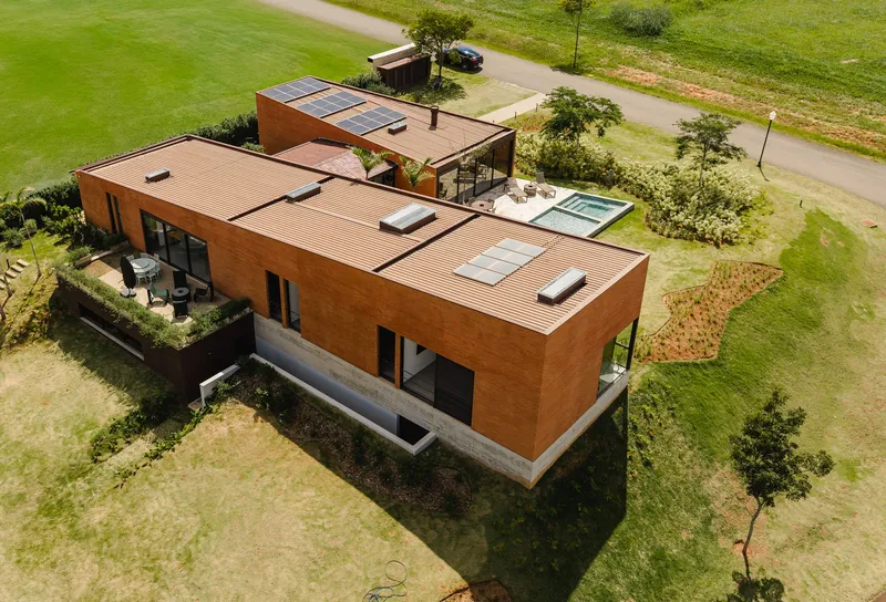 Aerial view of the horizontal brick volumes with corrugated metal roofs and skylights in open fields