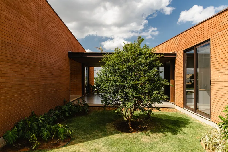 Interior courtyard with tree planted in lawn between brick walls and covered walkway
