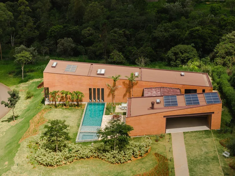 Aerial view of red brick barrel roof with solar panels and pool set in lawn