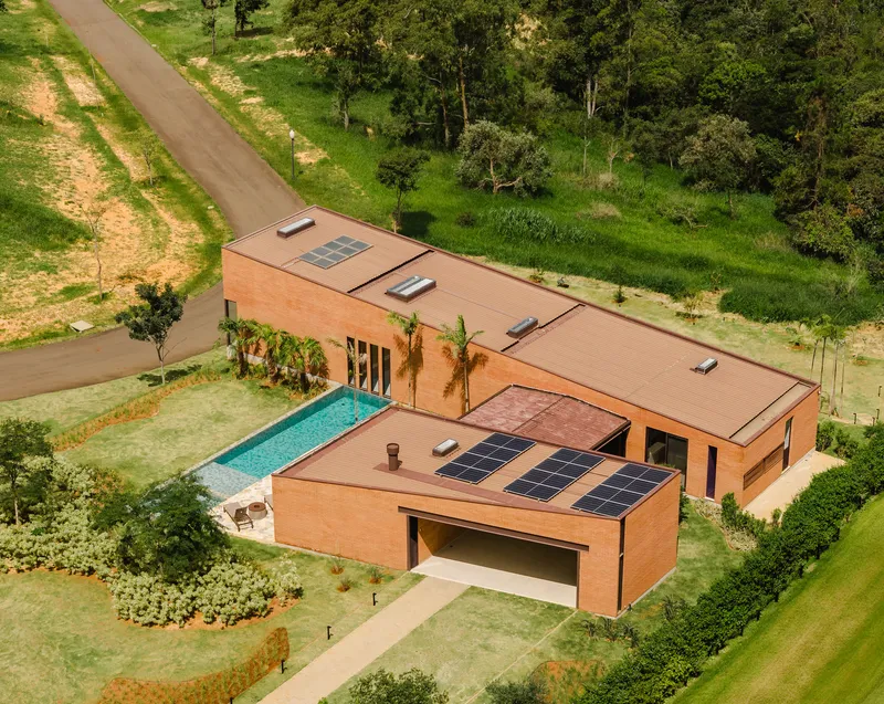 Drone perspective of the L-shaped volumes with photovoltaic arrays and lap pool beside the entry road
