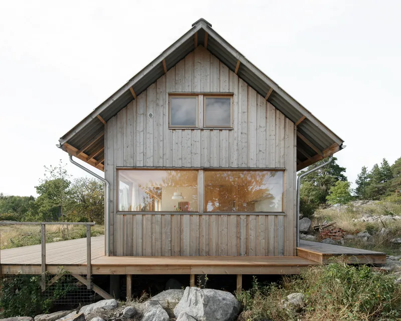 Gable end with vertical timber siding and horizontal strip window on an elevated deck platform