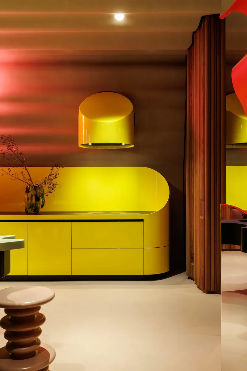 Yellow rounded cabinetry with golden dome light fixture against gradient pink and brown wall
