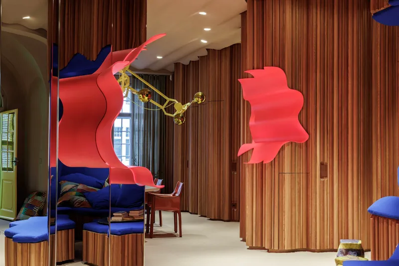 Interior space with curved timber slat partitions and suspended coral-colored sculptural panels
