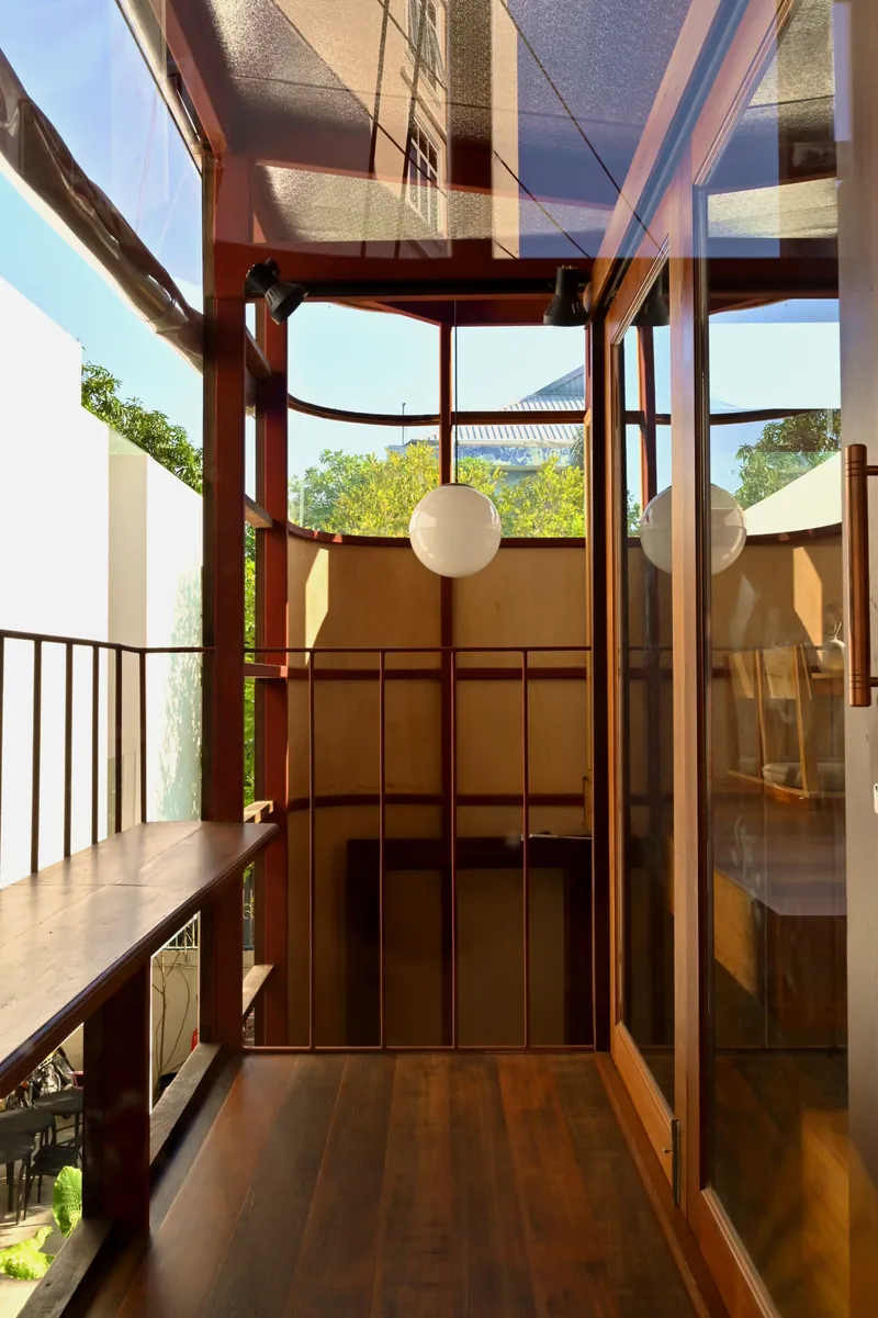 Glass enclosed stairwell with red steel frame opening to garden view in daylight