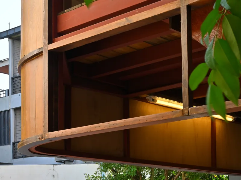Detail of cantilevered timber balcony with exposed joists and steel columns at dusk